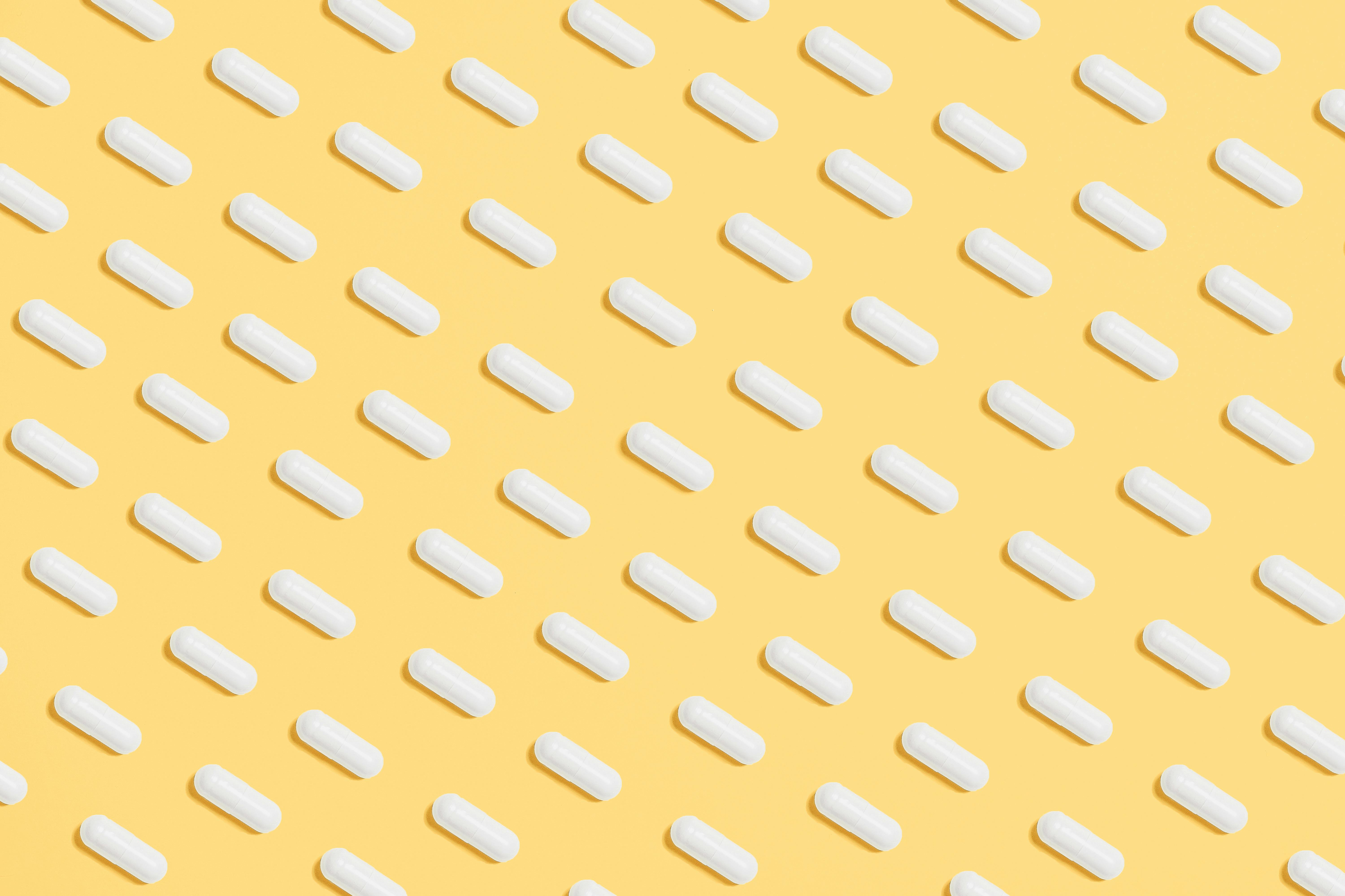 image of white pills spaced evenly on yellow backdrop 